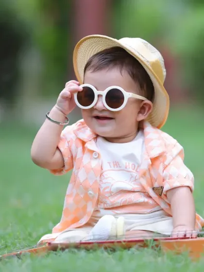 We capture your child's personality in our fun and stylish outdoor photoshoots. This cool little guy is rocking his shades in a natural park setting, perfect for candid and relaxed portraits.