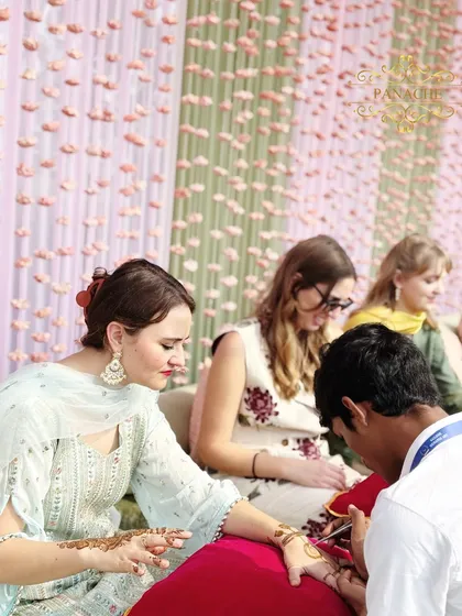Guests enjoying the traditional application of Mehndi, seated in a beautifully decorated area.