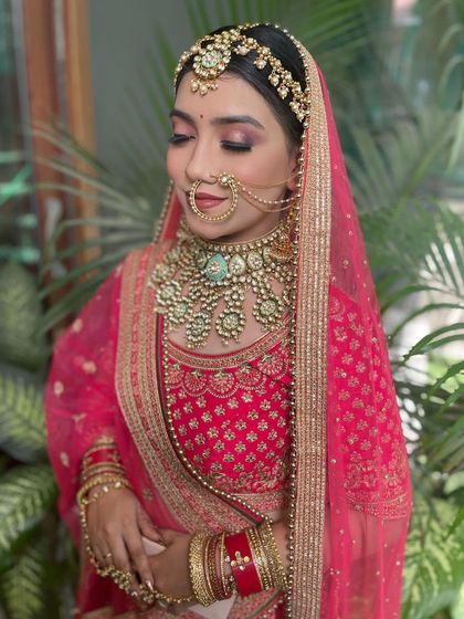 A serene bridal portrait featuring our pink rental lehenga and green-beaded jewellery. The soft glam makeup complements the elegant and colorful ensemble perfectly.