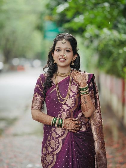 A stunning engagement look in a deep purple saree. The makeup features defined eyes and a neutral lip, perfectly complementing the rich color of her outfit.