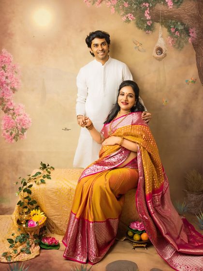 A classic couple's portrait set in a dreamy, artistic landscape. The couple holds hands, symbolizing their partnership and shared joy as they await their little one.