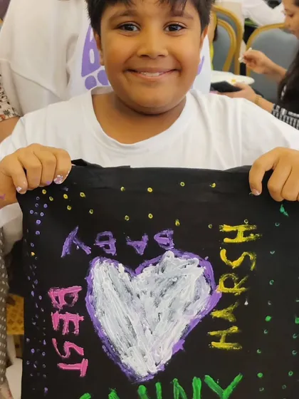 A young guest created a heartfelt message on a tote bag, showing that all ages can participate and contribute at a family event.
