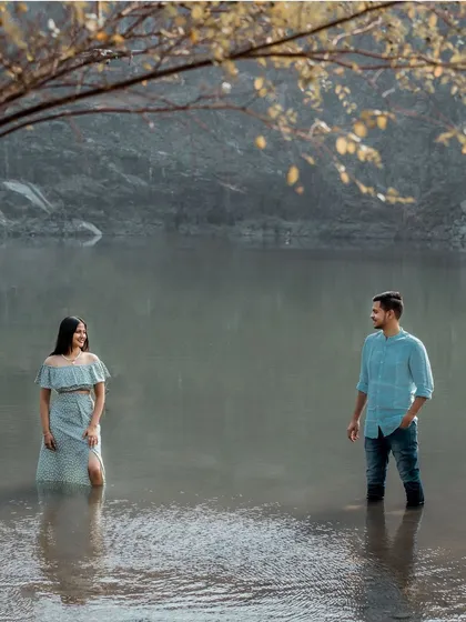 A creative and serene shot of a couple standing in the water, reflecting their calm and steady love for each other amidst a beautiful landscape.
