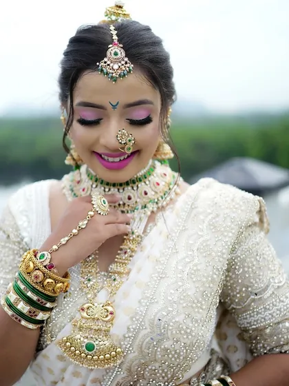 A smiling bride on the bridge. This shot showcases the full effect of the traditional jewelry and the elegant drape of the white saree, perfect for a Maharashtrian wedding.