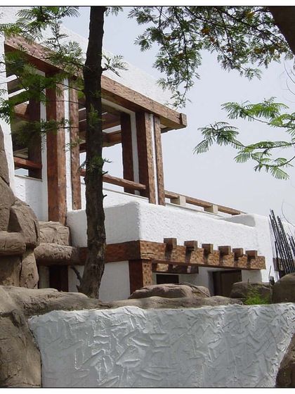 A closer look at the river rock style home. The integration of natural boulders with wooden beams and white stucco creates a rustic yet modern aesthetic that is deeply connected to the earth.
