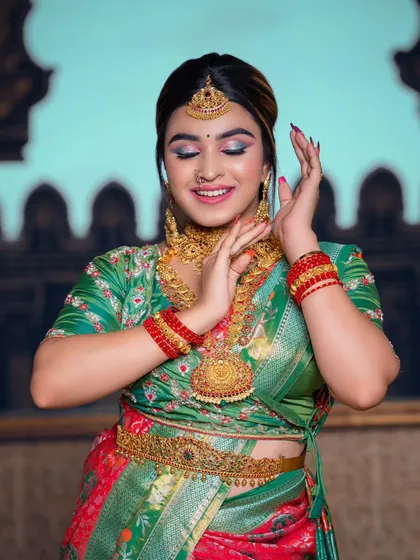 This student portfolio look features a beautiful green and red silk saree. The makeup includes a pop of blue on the eyes for a unique touch, paired with traditional gold jewellery.