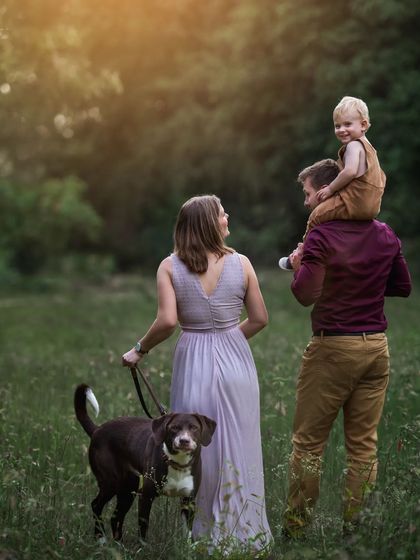A duplicate of ID 28, this candid outdoor shot captures a family's happy walk through a field at sunset, their dog trotting alongside them.