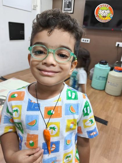 Check out that dino-mite accessory! This young explorer is thrilled with his hand-painted dinosaur tooth necklace, a perfect memento from our fun-filled dino workshop.