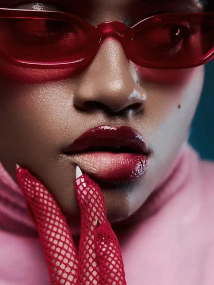 A macro beauty shot focusing on the lips and nails. The vibrant red tones and glossy textures are captured with sharp detail, making it ideal for a cosmetics campaign.