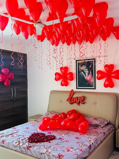A wider view of the all-red romantic room decoration, showing how the balloons and wall decor create a cohesive and loving atmosphere.