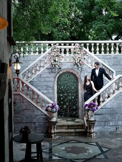 A grand, wide-angle shot of a couple on a beautiful stone staircase, creating a fairytale-like pre-wedding scene.