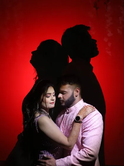 A creative couple portrait using their own shadows against a red background for a dramatic and artistic effect.