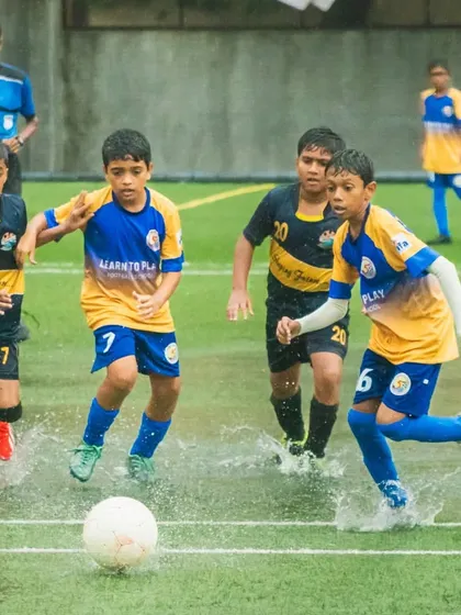An action shot from a U13 match in the Thane Youth League, playing through wet conditions.