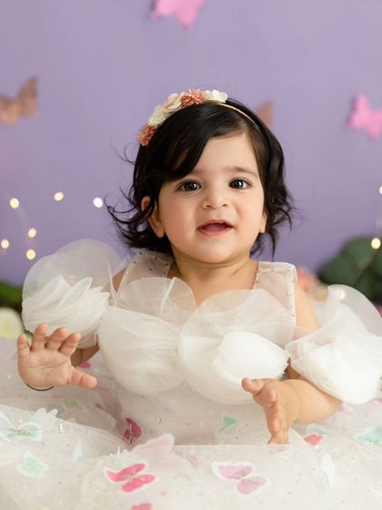 A close-up of the happy baby girl clapping her hands during her butterfly-themed birthday session.