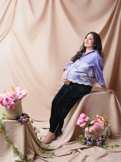 A relaxed and stylish portrait of the mother-to-be, with her partner's presence implied. The casual outfit and soft, warm lighting create a comfortable and modern feel.