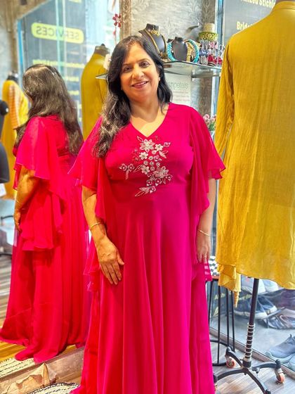 This vibrant pink gown is perfect for any celebration. It features delicate floral embroidery on the bodice and graceful, ruffled cape sleeves that add a touch of drama and movement.