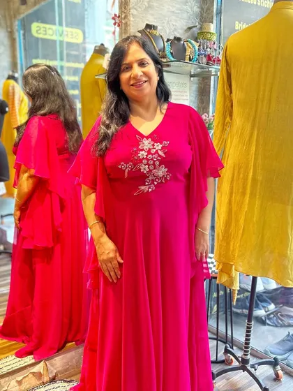 A client looking radiant in a custom-embroidered fuchsia gown with graceful ruffled sleeves. I designed this piece to be both comfortable and glamorous for any festive gathering.