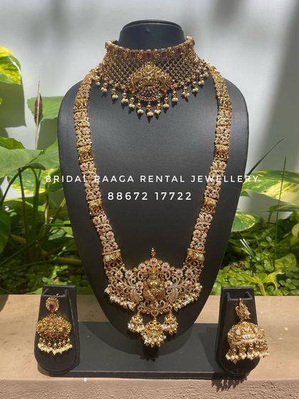 This unique set combines a detailed choker with a long haram featuring elephant and floral motifs. The sparkling stones add a touch of glamour to the traditional design.