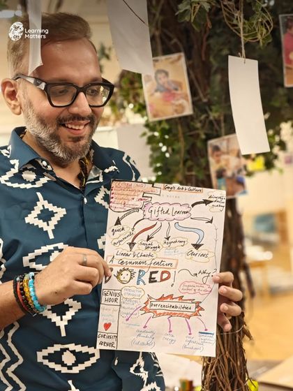 A participant in our "Beyond the Bright" workshop proudly displays a mind map detailing the complexities of gifted learners. This visual tool captures key concepts discussed, such as asynchronous development and the importance of addressing boredom with possibilities.