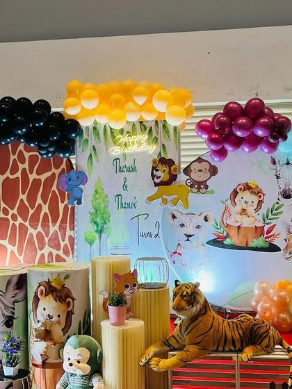 A creative jungle theme for a joint birthday, using a giraffe print arch and multiple character props.