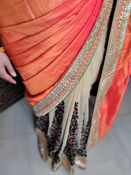 A close-up of an open pallu draping on a half-and-half designer saree. The pleats are neatly arranged to showcase the transition between the two fabrics.
