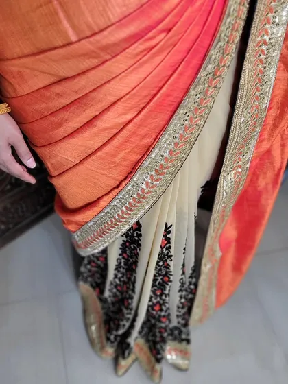 A close-up of an open pallu draping on a half-and-half designer saree. The pleats are neatly arranged to showcase the transition between the two fabrics.