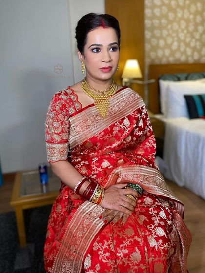A sitting portrait of the bride, showing how the simple updo complements her heavy gold jewelry and traditional attire.