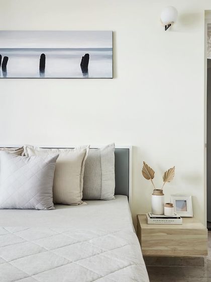 A detail shot of the master bedroom's bedside table. The minimalist decor, including a simple vase and framed photo, complements the room's tranquil and uncluttered Scandinavian vibe.