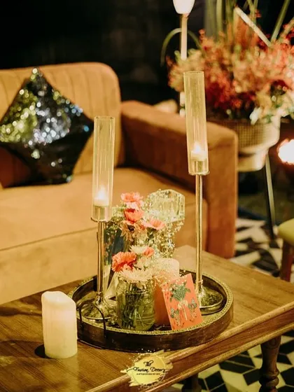 A simple yet elegant centerpiece for a lounge table, featuring tall, slender candle holders and a small floral arrangement. It adds a touch of sophistication without overwhelming the space.