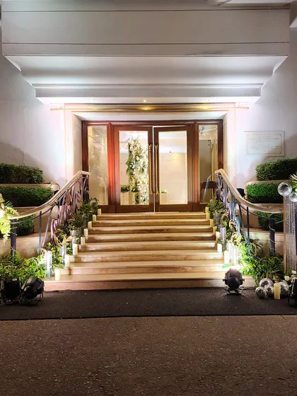 The venue's grand staircase decorated for an evening event. The steps are lined with greenery and candles, leading up to a beautifully lit entrance that promises a magical night ahead.