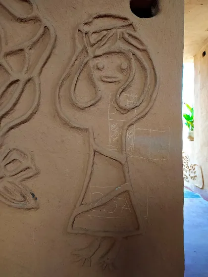 A whimsical figure sculpted from mud on the wall of a homestay in Madhya Pradesh. These murals, often made by the women of the family, tell personal stories and add a unique, artistic touch to each building.
