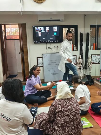 A group of DNYS students engaged in a practical session on measuring blood pressure, an essential skill for any wellness professional.