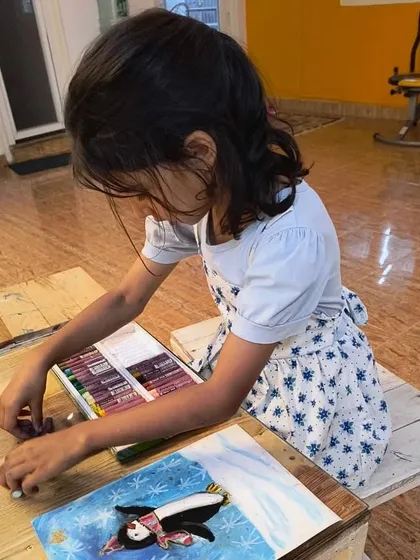 A student carefully works with soft pastels to create a charming penguin illustration, learning how to blend colors for a soft, snowy effect.