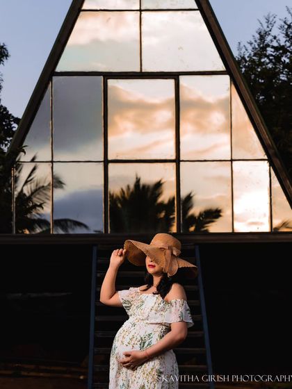 A stylish and modern maternity shot. The unique A-frame architecture provides a stunning graphic background, especially as it reflects the sunset, while the hat adds a touch of chic personality.