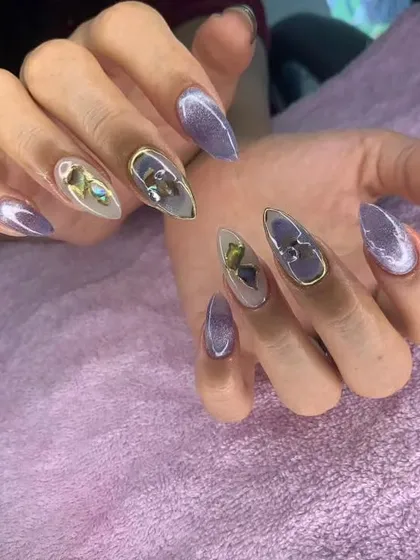 A beautiful purple cat eye set with 3D butterfly and gold chrome accents on stiletto nails.