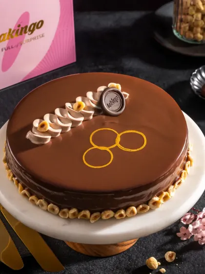 A hazelnut chocolate cake with a mirror glaze finish, shown with its branded packaging, ideal for e-commerce and brand-focused marketing.