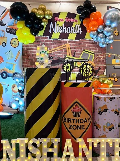 A fun and detailed construction-themed 5th birthday party. This setup is packed with details like a custom backdrop, themed props including a dump truck and traffic cones, and marquee letters, perfect for any little builder.