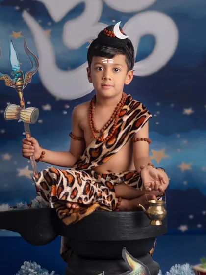 A powerful and serene portrait of a young boy dressed as Lord Shiva, holding his trishul.