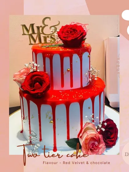 This two-tier wedding cake makes a bold statement with its vibrant red drip over pristine white frosting. Topped with fresh roses and a "Mr & Mrs" sign, it’s a perfect blend of modern style and classic romance.