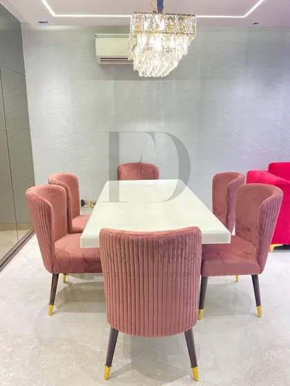 This dining set is perfect for a modern home, featuring a white onyx table with a sculptural gold base. The chairs, upholstered in a pleated rose-colored velvet, add a pop of color and texture.