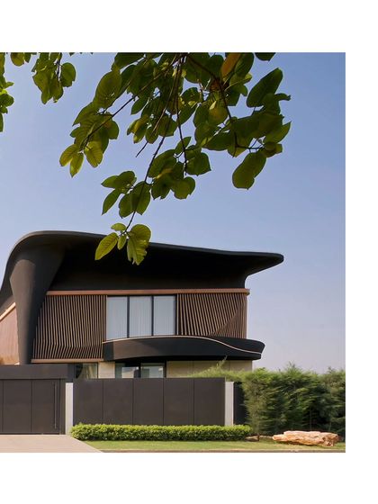 The fluid roof of Residence Ondra appears to float above the structure, a signature element of its design. Framed by lush foliage, the home's organic shape and textured facade create a harmonious dialogue with nature.