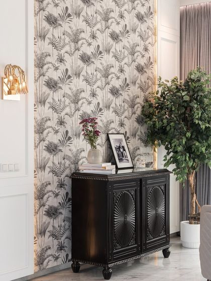 A beautiful corner where vintage meets modern. We paired an intricately carved black cabinet with an eclectic, tropical-print wallpaper, creating a look that is both timeless and full of personality.