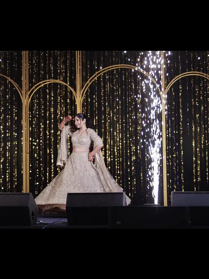 The bride shines during her solo sangeet performance. Her graceful twirl and the sparkling stage effects make for a magical and captivating photograph.