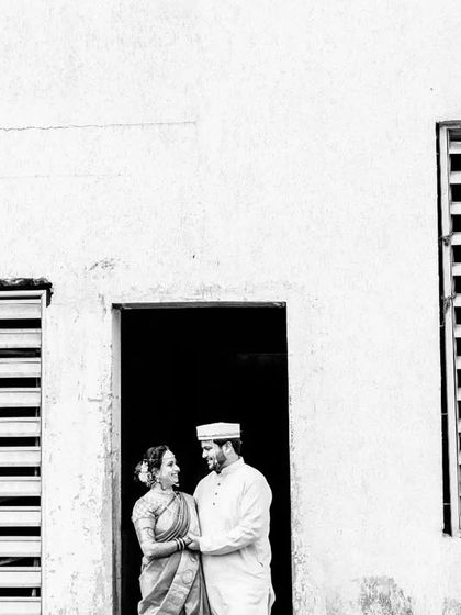 A minimalist black and white portrait of the couple framed in a doorway, creating a simple yet powerful composition.