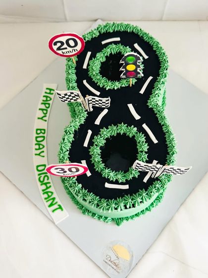 A creative number "8" cake designed to look like a racetrack for a car-loving birthday boy.