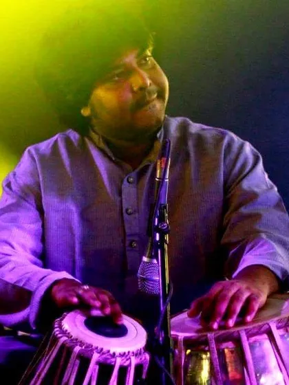A close up shot capturing a moment of soulful expression during a live concert. The warm, yellow and purple stage lighting adds to the mood of the performance.