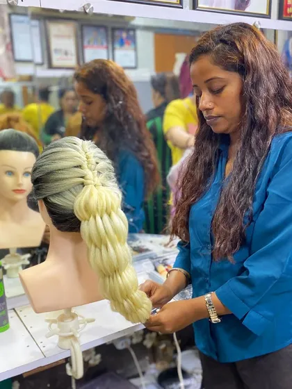 A student working on a bubble braid with blonde extensions. Our classes cover techniques for working with extensions to add length and volume.