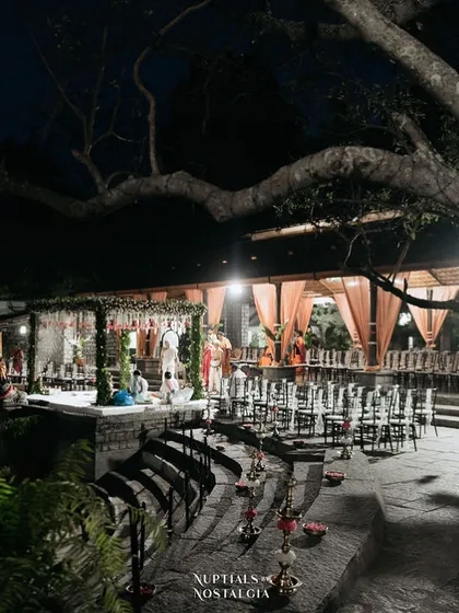The Pond Pavilion at night, set up for a ceremony with elegant lighting and seating on the stone steps.