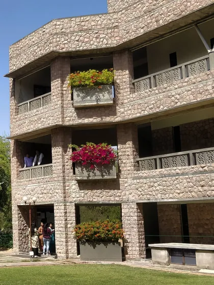 The building facade shows balconies with flowering plants, integrating nature at every level. This project was the winning entry in a design competition and was later nominated for the Aga Khan Award for Architecture.