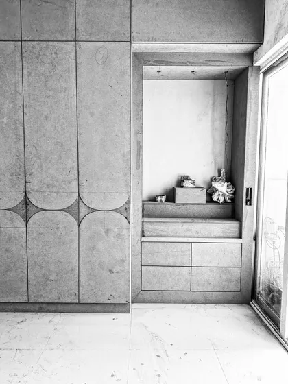 A black and white photo of a work-in-progress bedroom, showing a custom wardrobe with curved groove details next to a built-in mandir space. This image captures the raw structure and craftsmanship before the final finishes are applied.